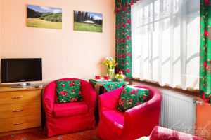 Fotografia biznesowa Zakopane. Zdjęcie pokoju z czerwonym elementami w góralskim stylu.