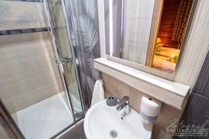 Zdjęcia pensjonatu Zakopane. Ujęcie przedstawia łazienkę, w lustrze odbija się część pokoju.