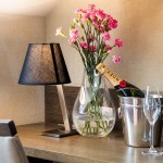 Sesje reklamowe hoteli. Zdjęcie dekoracji, oraz wyposażenia pokoju: lampka, dekoracja kwiatowa, szampan, kieliszki, czajnik.