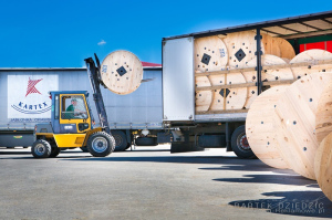 Zdjęcie przedstawia załądunek bębna na samochód ciężarowy.